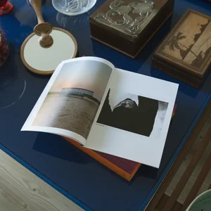 Open magazine on a blue coffee table with various objects. Magazine shows still life photography on one side, portrait photography on the other.
