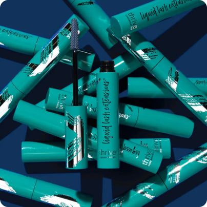 A pile of Liquid Lash Extensions from Thrive Causemetics, shot in studio in front of a blue background.