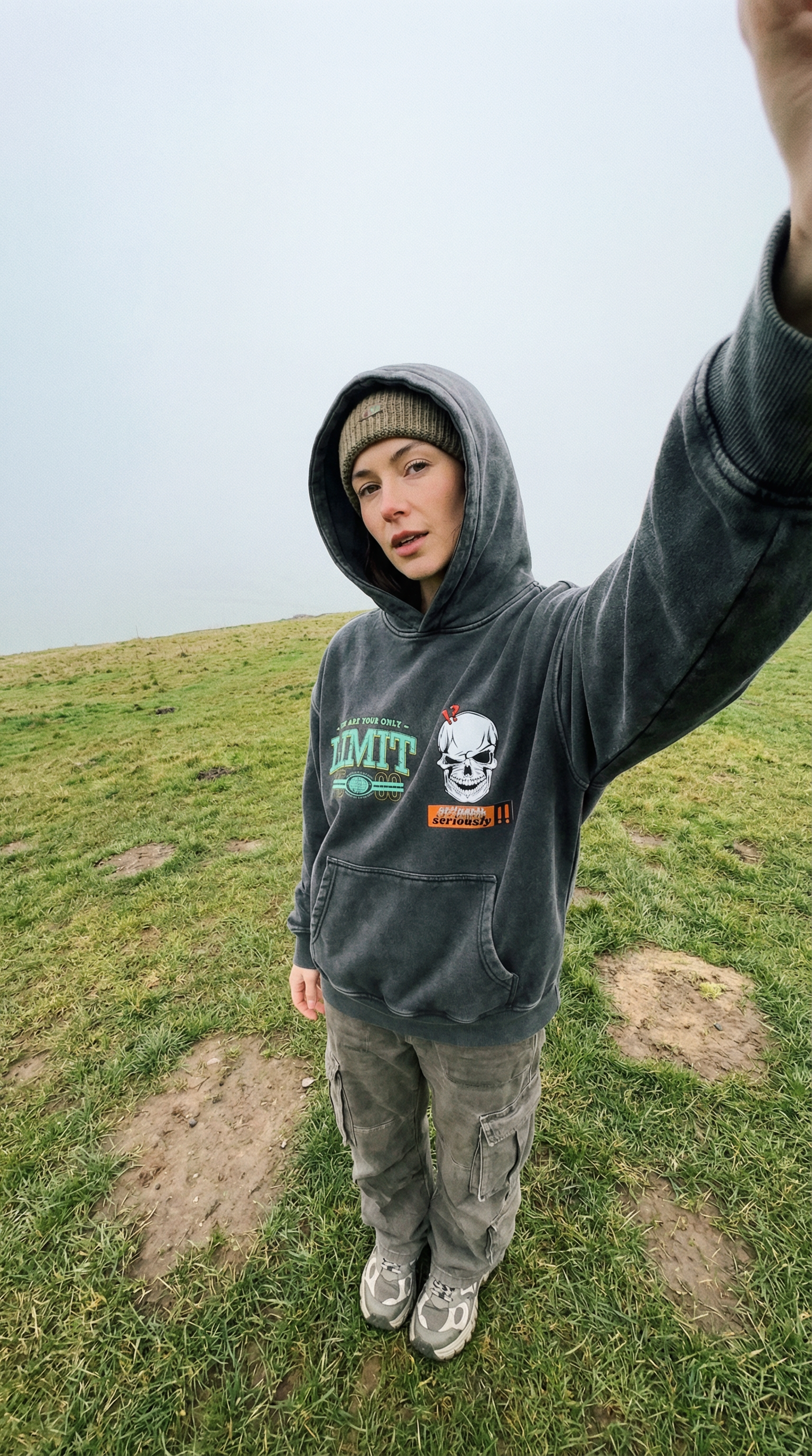 Person wearing a hoodie with a skull design on a grassy field cftdirect.com