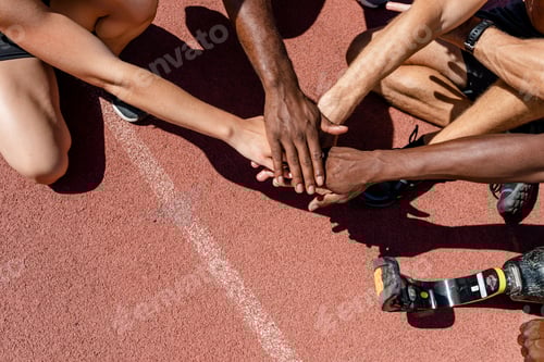 Preview: Team of diverse athletes stacking hand before the race