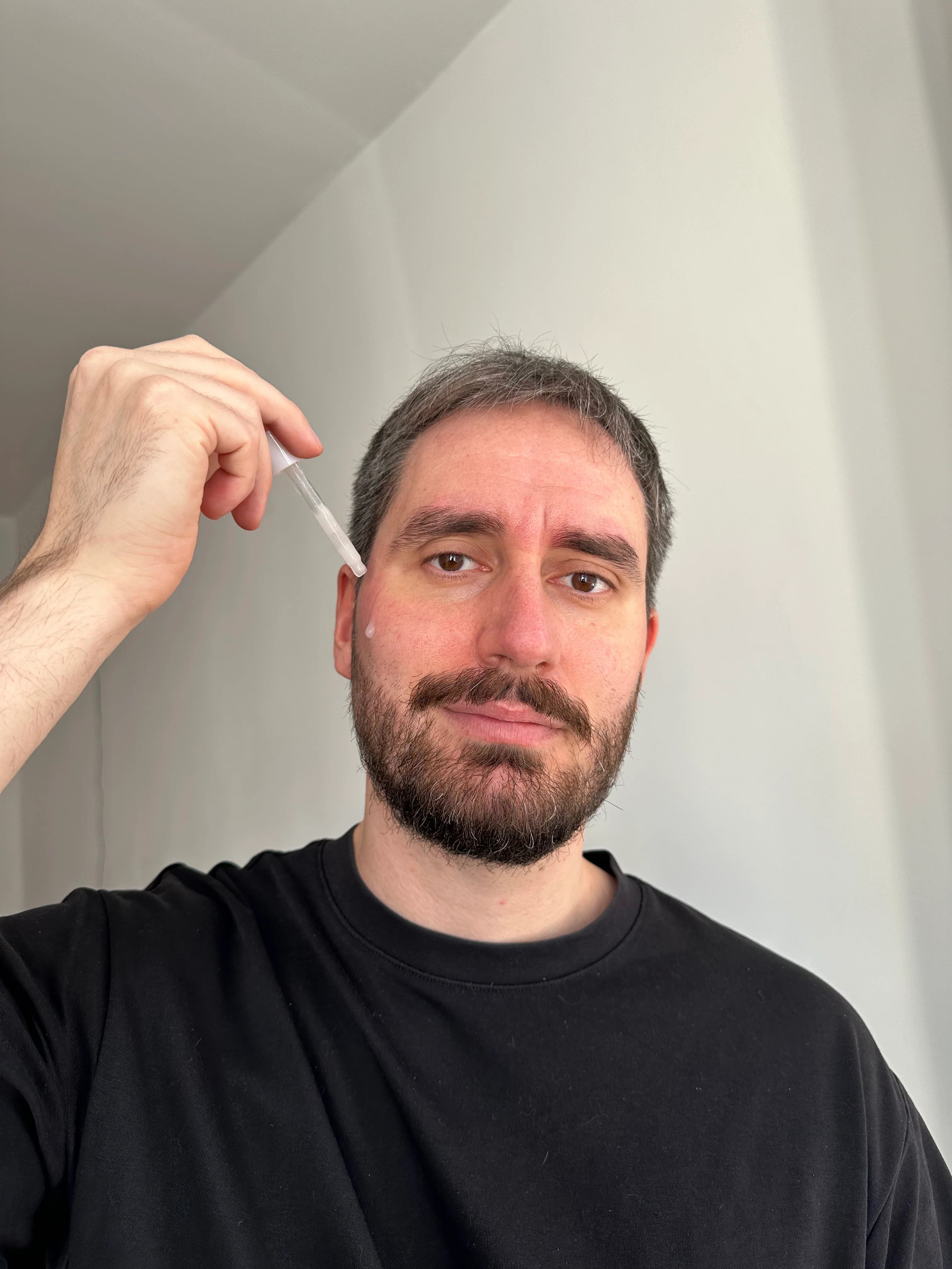 Een man brengt een serum van Rosental Organics aan op zijn gezicht.