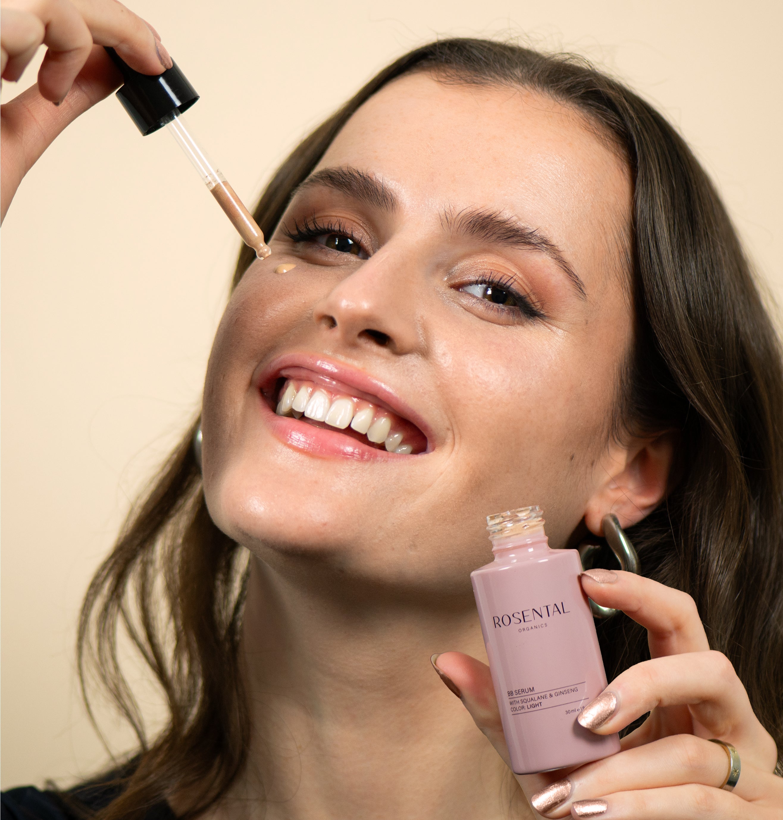 Een lachende vrouw brengt het Skin Perfecting Set van Rosental Organics aan voor een egale huid.