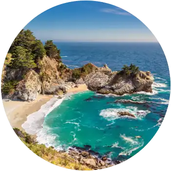 Waves flow out from an enclave surrounded by rock formations at Julia Pfeiffer Beach in the daytime.