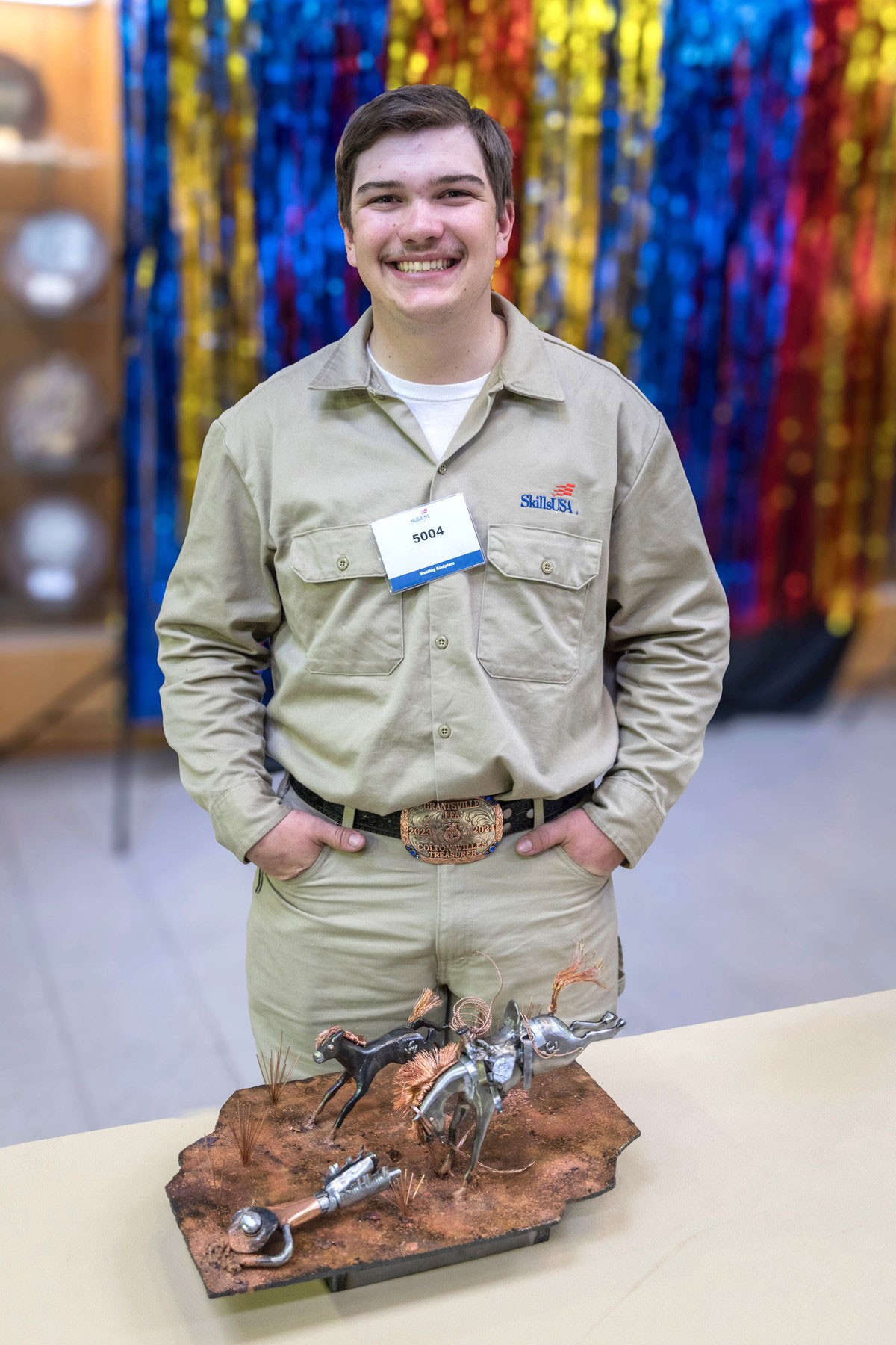 Colton Willes poses behind a welded sculpture on a table.